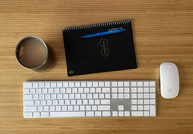 A mug, notebook, keyboard and mouse for sourcing content